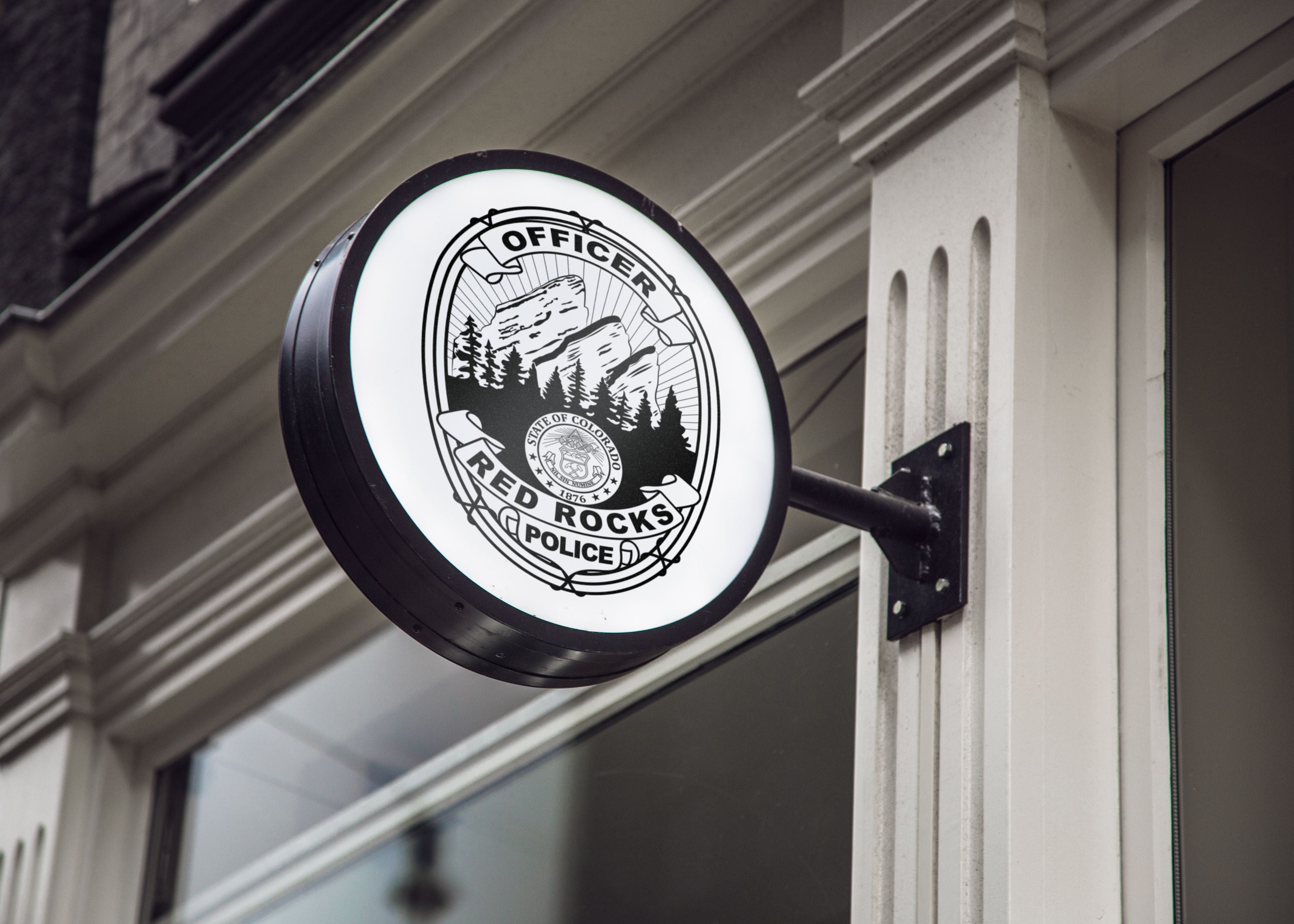 Round sign with 'Red Rocks Police' logo on a building facade