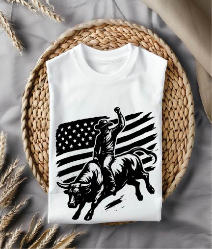 White t-shirt with a black graphic of a bull rider and American flag on a woven mat.